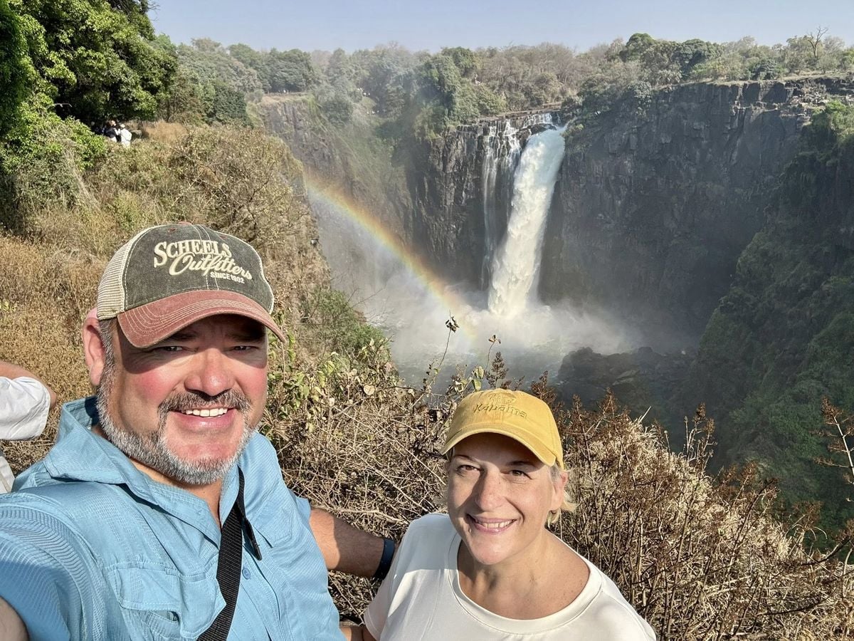 Travellers at Victoria Falls with a rainbow in the spray