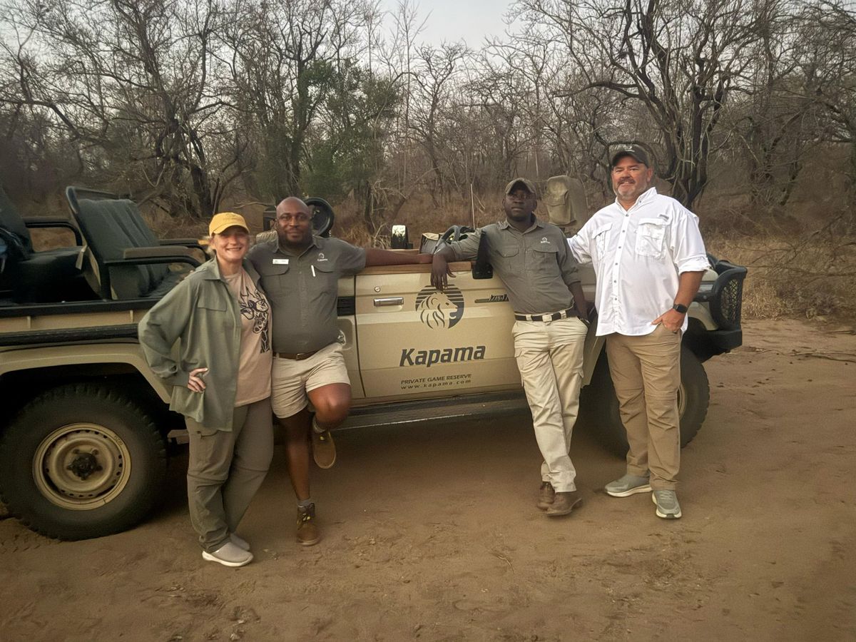 Travellers with their guides beside a game-drive vehicle at Kapama