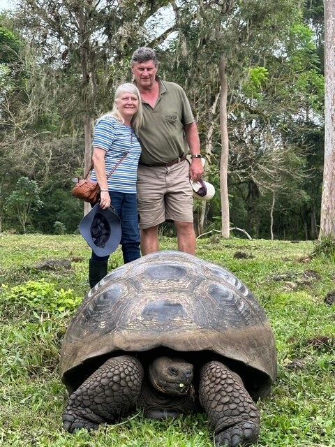 A couple with a giant tortoise in the Galapagos highlands