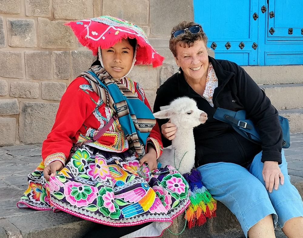 A traveller with a baby alpaca in the streets of Cusco