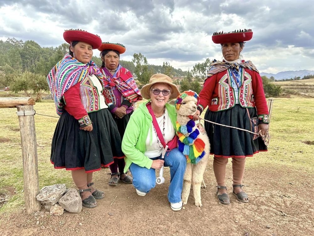 A traveller with local weavers and an alpaca in Chinchero