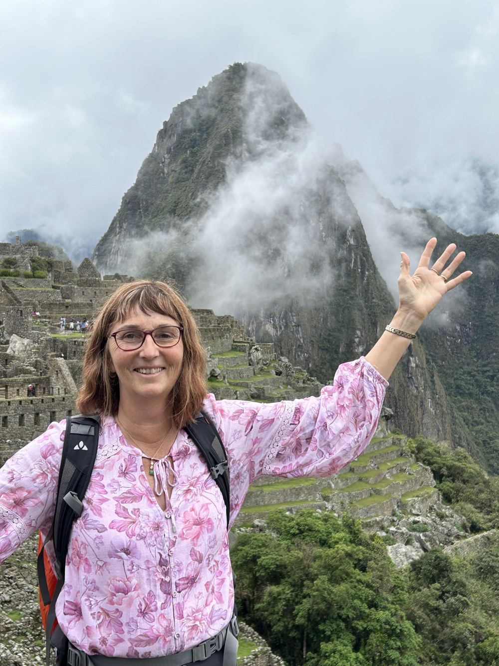 A traveller waving in front of Huayna Picchu in the mist