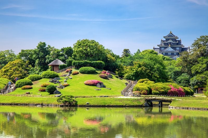 Manicured lawns and pond of Korakuen Garden with Okayama Castle beyond