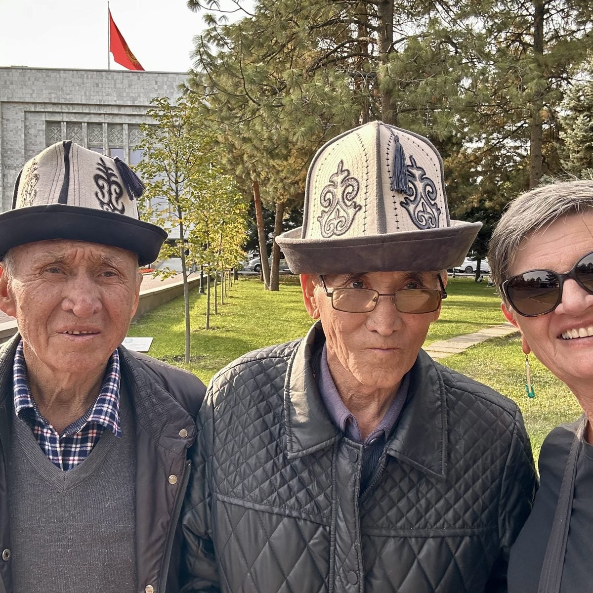 A traveller with local Kyrgyz men in traditional kalpak hats